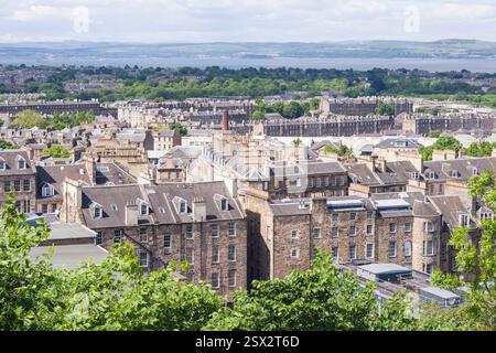 A scenic view of historic buildings in Edinburgh viewed from Calton Hill, UK, with classic stone buildings, rooftops, and lush greenery. Stock Photo