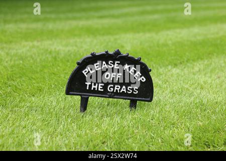 Please keep off the grass. Vintage cast iron sign on a well-kept lawn in a UK park Stock Photo