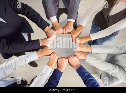 Team Members Engaging in a Collaborative Fist Bump Circle During a Corporate Meeting Stock Photo