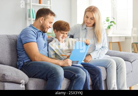 Mother, Father, And Son Drawing And Doing Homework Together At Home Stock Photo