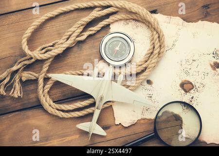 airplane, old map, compass with magnifier on wooden table Stock Photo
