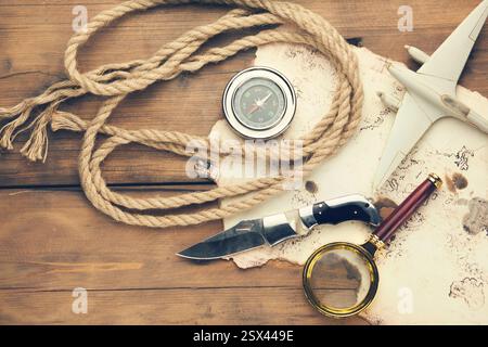 airplane, old map, compass,knife with magnifier on wooden table Stock Photo