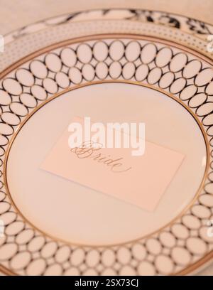 A beautifully arranged plate with delicate patterns, showcasing a name card for the bride, set at a wedding table. Stock Photo