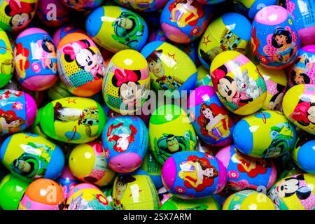 Colorful plastic eggs featuring beloved cartoon characters scattered on bright surface during festive celebration Stock Photo