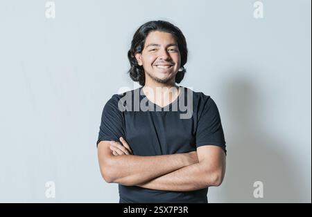 Portrait of handsome latin man with arms crossed isolated. Young latin man smiling at camera Stock Photo