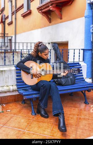Photo of a young woman playing acoustic guitar on a park bench Stock ...