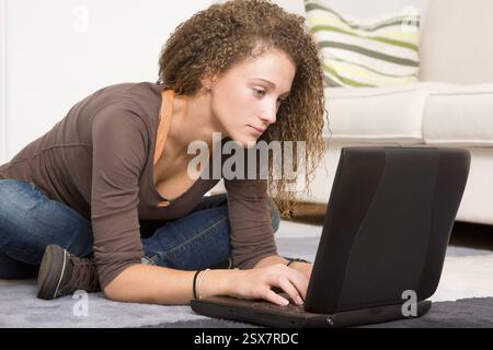 Young woman sitting cross-legged in front of her laptop Stock Photo