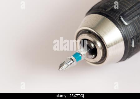 Cordless screwdriver with screwdriver bit on light background close-up, screwdriver chuck with bit Stock Photo