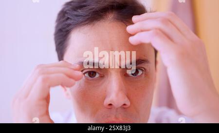 Worried man checking hair loss and touching forehead Stock Photo