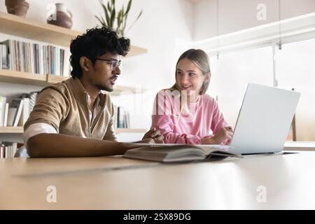 Schoolmates discuss joint task sit at desk with laptop Stock Photo