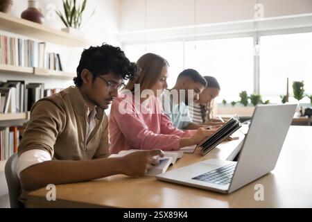 Serious students studying seated at table in library or classroom Stock Photo