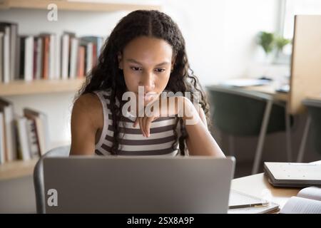 Student engaged in e-learning seated table with modern laptop Stock Photo