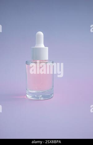 Mockup of face serum in glass dropper bottle on blue background. Skin care treatment package. Stock Photo