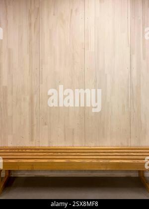 Empty Wooden Bench Against a Plain Wooden Wall in a School Stock Photo