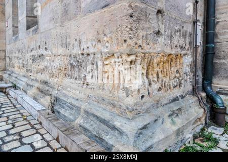 The base stones of the collegiate church of St. Martin in Forchheim show deep weathering and eroded pores in the sandstone. The Gothic church has its roots in a Carolingian royal chapel. A synod took place here in 890. Bishop Leopold von Bebenburg raised it to collegiate status in 1354. Paradeplatz, Forchheim, Bavaria, Germany. Stock Photo