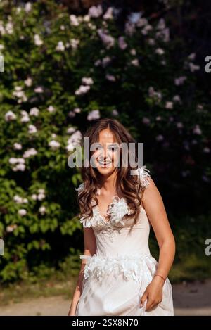 Stunning bride gracefully poses in a spring park, among blossoming trees. exuding elegance, Stock Photo