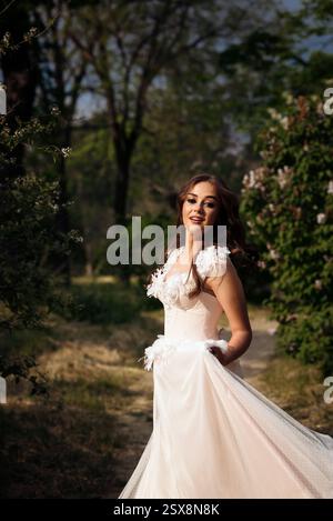 Stunning bride gracefully poses in a spring park, among blossoming trees. exuding elegance, Stock Photo