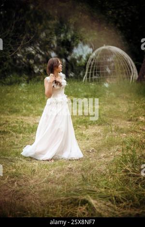 Stunning bride gracefully poses in a spring park, among blossoming trees. exuding elegance, Stock Photo