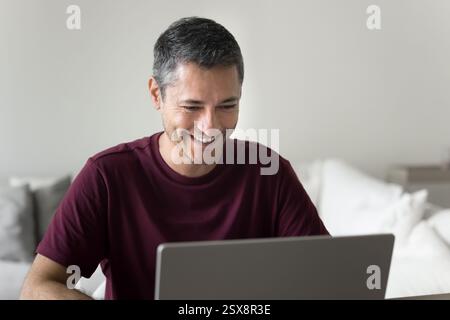 Young man sitting at desk working or studying using laptop Stock Photo
