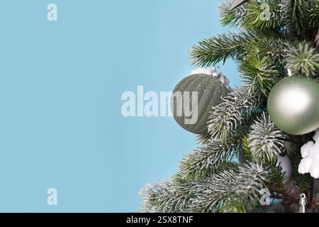 Close up of decorated Christmas tree with seasonal sage green tree ornament baubles on blue background with copy space Stock Photo