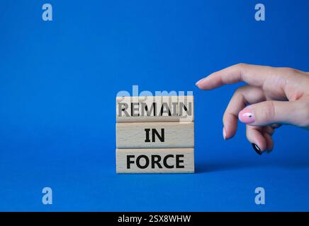 Remain in Force symbol. Concept words Remain in Force on wooden blocks. Businessman hand. Beautiful blue background. Business and Remain in Force conc Stock Photo