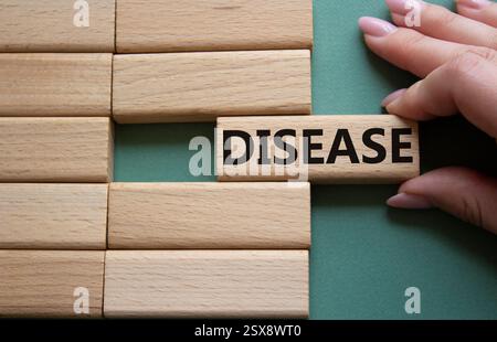 Disease symbol. Concept word Disease on wooden blocks. Doctor hand. Beautiful grey green background. Medicine and Disease concept. Copy space. Stock Photo