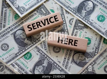 Service here symbol. Concept words Service here on wooden blocks. Beautiful dollar background. Business and Service here concept. Copy space. Stock Photo