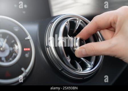 Finetuning the Air Vent in Your Car for Maximum Comfort During Every Drive Experience. A hand skillfully adjusting a cars air vent for enhanced airflo Stock Photo