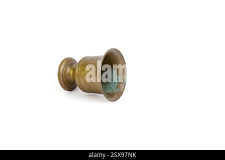 Vintage brass cup tilted,  overturned and spilling on white background, abstract  backdrop Stock Photo