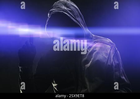Computer hacker in hoodie using virtual screen. Database hacking, computer virus malware and cybersecurity concept. Selective focus. Stock Photo