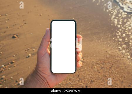 Smartphone mockup at seaside, man using mobile phone on sandy beach, selective focus Stock Photo