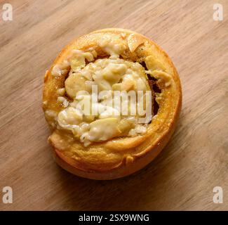 A delicious tosca roll sits on a wooden surface, generously drizzled with creamy icing. The warm pastry invites indulgence with its sweet aroma Stock Photo