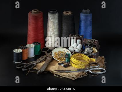 Thimbles in small wooden treasure chest, Spools of thread of various colour, Sewing needles stuck in a green miniature spools thread, Steel scissors a Stock Photo