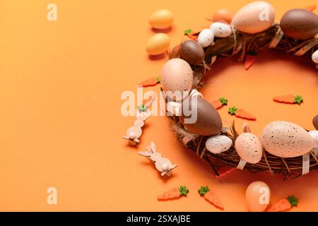 Easter wreath made of eggs and feathers on orange background Stock Photo