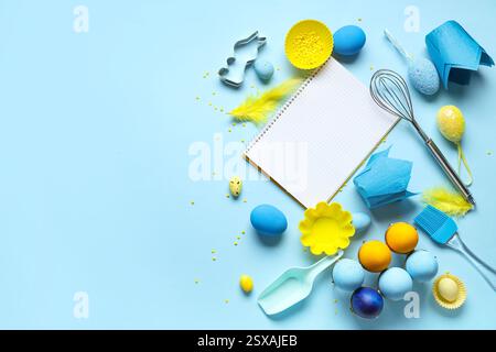 Blank notepad for recipes with baking tools and Easter eggs on blue background Stock Photo