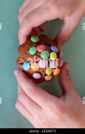 Close-up of two children's hands holding an Easter baked muffin with colorful decorations Stock Photo