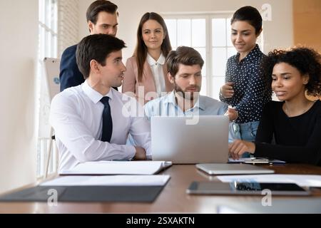 Staff using laptop working together on joint task Stock Photo
