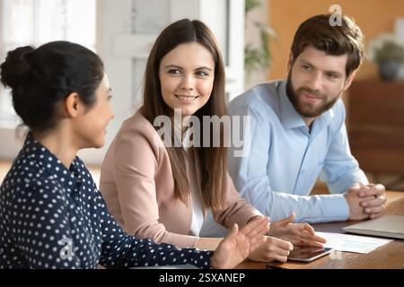 Three multinational teammates lead conversation about work related matters Stock Photo