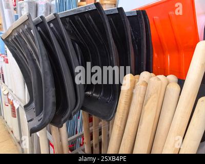 A variety of shovels and wooden handles are organized in a hardware store. The tools are lined up on a display, showcasing their sturdy designs and co Stock Photo