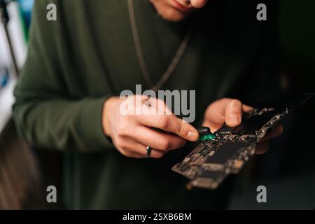 Cropped shot of unrecognizable technician male carefully cleaning laptop motherboard with a small brush. Concept delicate process of hardware Stock Photo