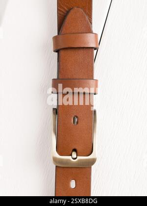Brown genuine leather belt on a white wooden background. Stock Photo