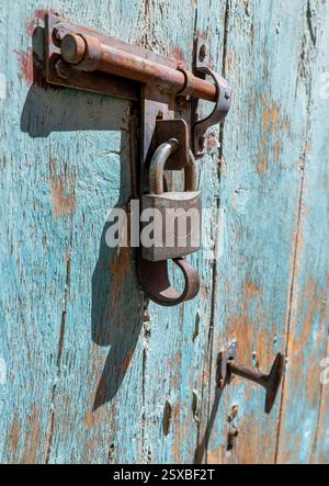 Close-uo of an iron bolt with padlock on an old wooden door. Stock Photo