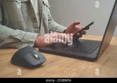 Closeup image of a man using a laptop and phone on the wooden desk table, business concept. Stock Photo