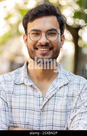 Portrait of happy smiling Indian young man looking at camera, resting, relaxation feel satisfied glad expression of good news outdoors. Hispanic guy tourist on urban city street. Town lifestyles. Stock Photo