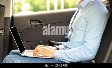 Handsome arabic entrepreneur sitting at auto, using laptop, mockup Stock Photo