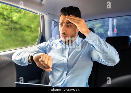 Worried arab businessman looking at watch while sitting in car Stock Photo