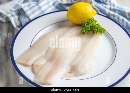 Raw boneless skinless  Sole on a plate with a lemon and fresh parsley garnish . Stock Photo