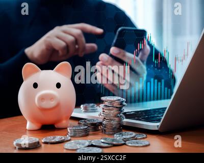 Investment online trading application, business financial concept. Piggy bank with many coins on table while businessman, broker using mobile smart ph Stock Photo