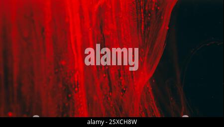 Blur falling flow. Water paint dripping. Defocused red color shine liquid drops smoke texture wave on abstract art dark black background. Stock Photo