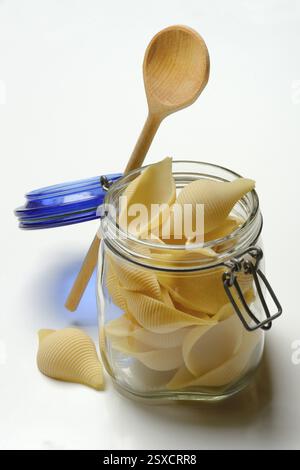 Conchiglione in glass jar with cooking spoon, Italian pasta variety Stock Photo
